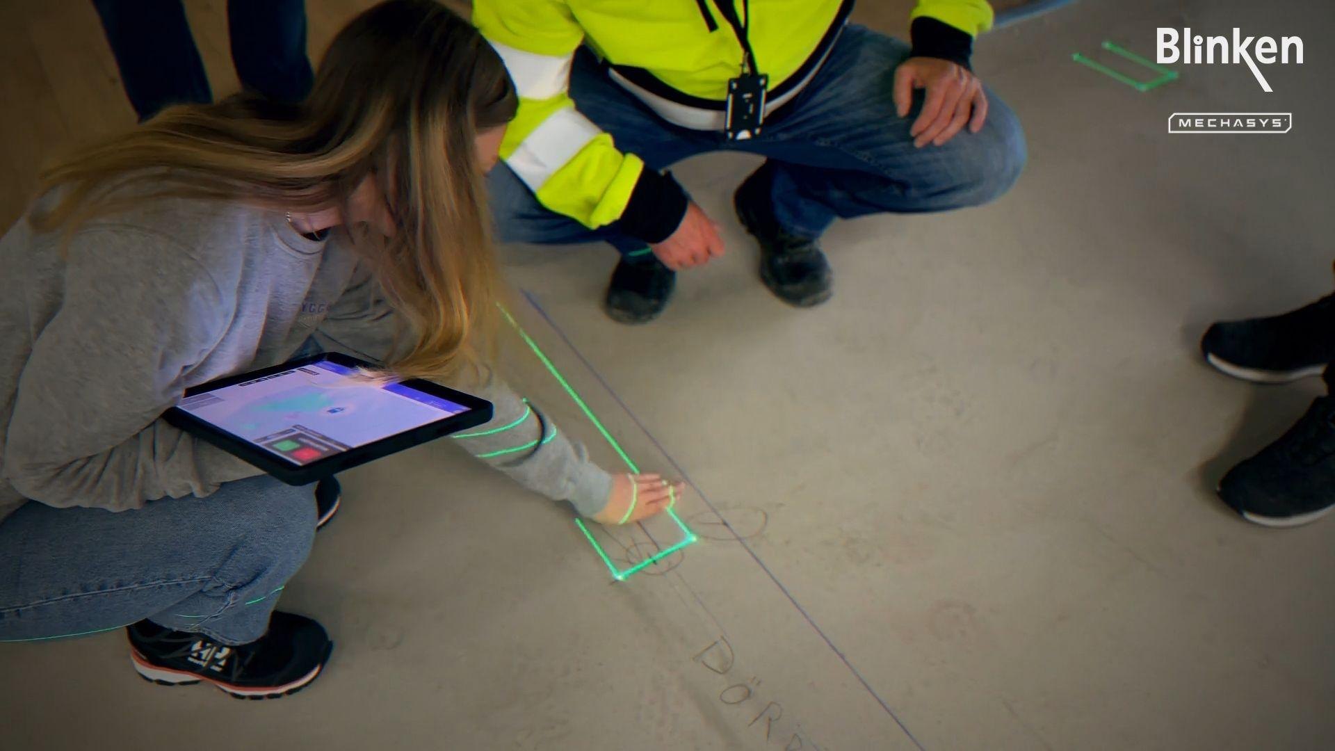 Operatör med surfplatta vid laserlinjen på golvet.